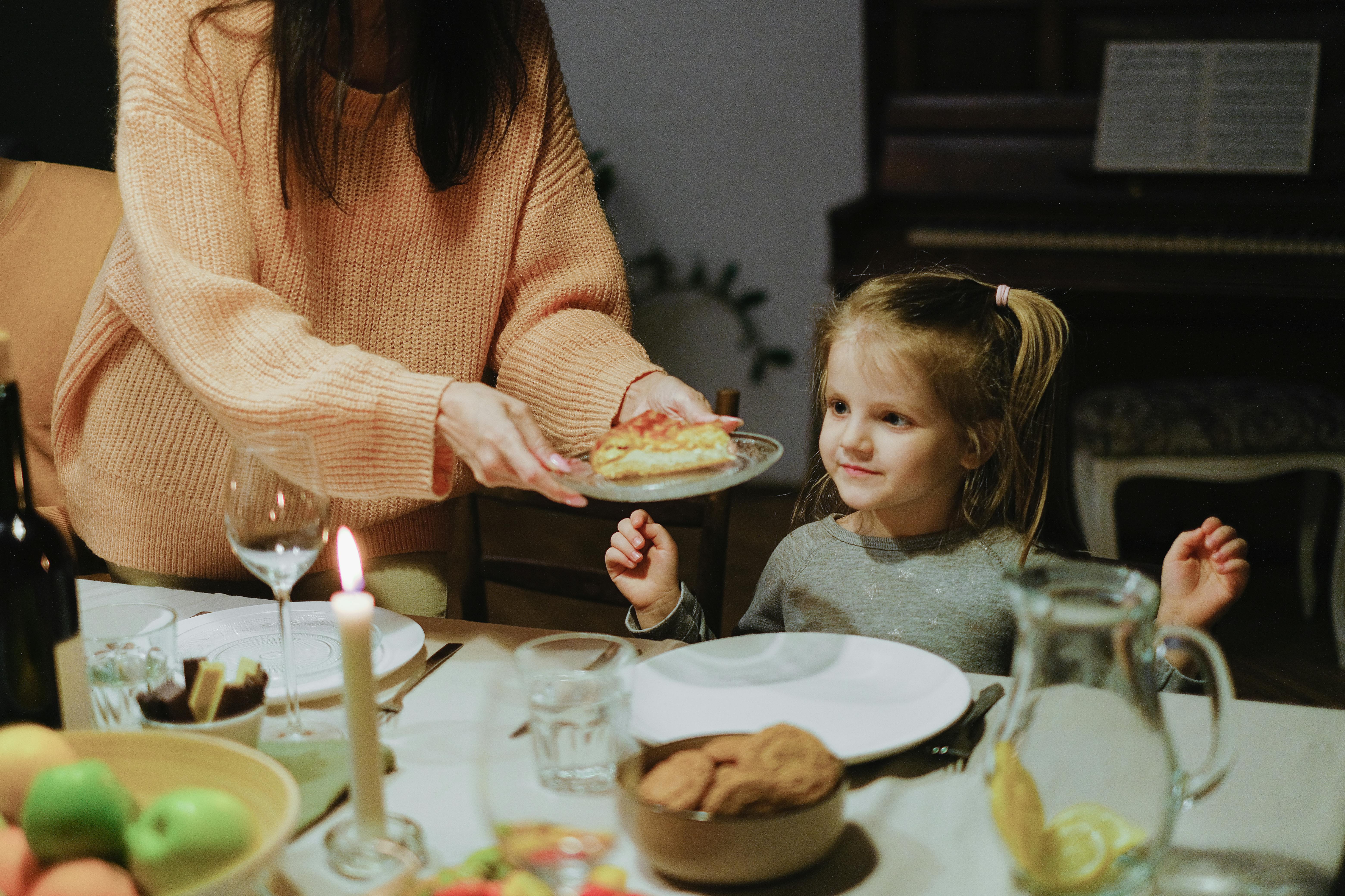 A mom serving her toddler dinner at the dining table to represent a post about easy dinner ideas for busy moms.
